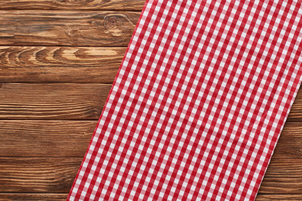 top view of red checkered napkin on wooden brown table