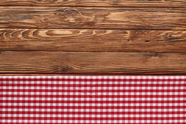 top view of red checkered napkin on wooden brown table