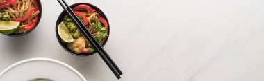 top view of delicious meat and vegetable thai noodles with chopsticks on marble grey surface, panoramic shot clipart