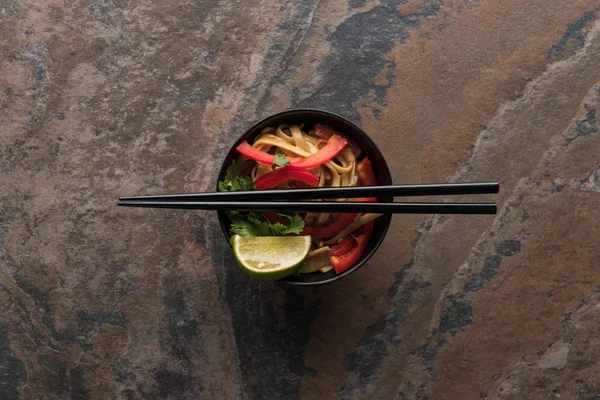石の表面に箸を入れたおいしいスパイシーなタイ麺のトップビュー — ストック写真