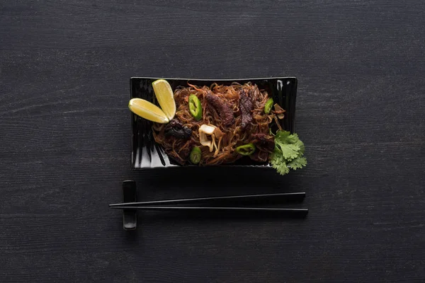 靠近木灰表面筷子的美味辣肉泰面的顶部视图 — 图库照片