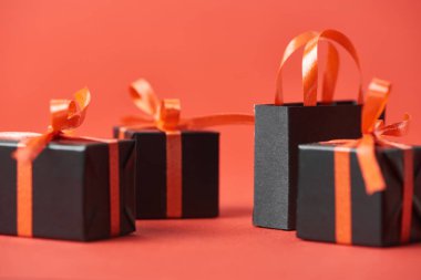 Kırmızı arkaplanda Kara Cuma hediyelerinin ve alışveriş çantalarının görüntüsünü kapat