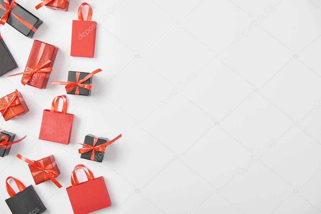top view of black and red presents and shopping bags on white background