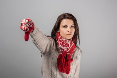 Kırmızılı ve eşarplı hoşnutsuz kadın baş parmağını gri renkte gösteriyor. 