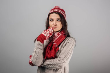 Kırmızılı düşünceli kadın, gri üzerine eldiven ve eşarp örmüştü. 