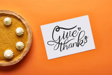 top view of pumpkin pie and card with give thanks illustration on orange background clipart
