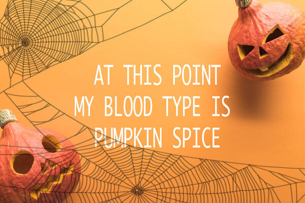 top view of spooky carved Halloween pumpkins on orange background with at this point my blood type is pumpkin spice illustration