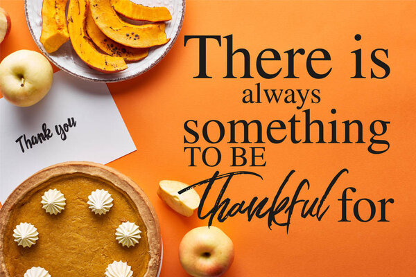top view of pumpkin pie, ripe apples and thank you card on orange background with there is always something to be thankful for illustration