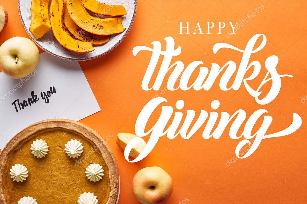 top view of pumpkin pie, ripe apples and thank you card on orange background with happy thanksgiving illustration