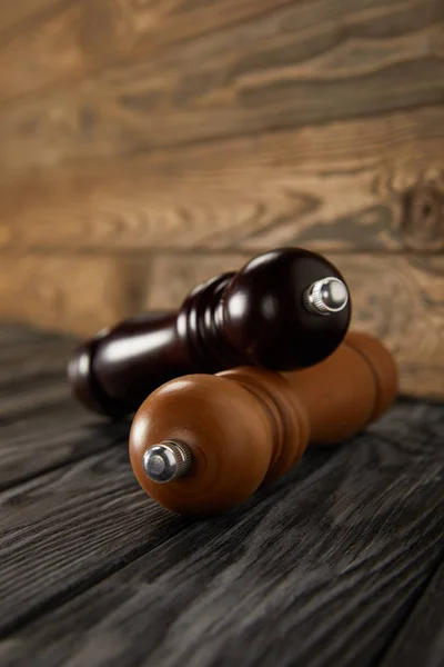 Wooden pepper grinder and salt grinder on wooden floor — Stock Photo