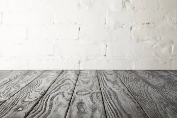 Grey wooden surface and white wall with bricks — Stock Photo