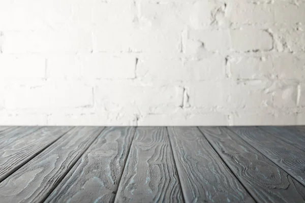 Piano in legno grigio e parete bianca con mattoni — Foto stock