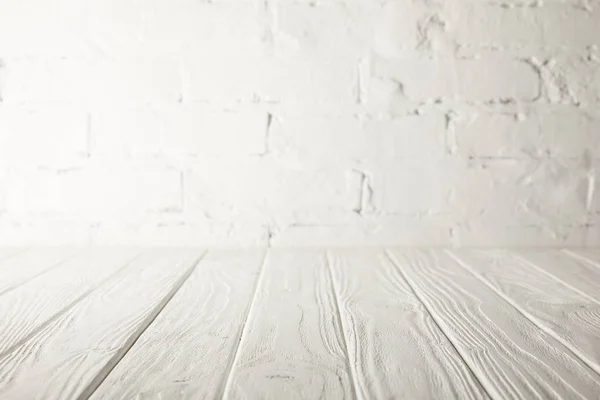 Mesa de madera blanca y pared blanca con ladrillos - foto de stock