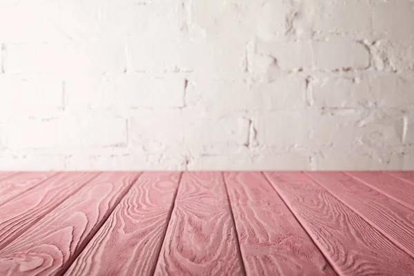 Pink wooden tabletop and white wall with bricks — Stock Photo