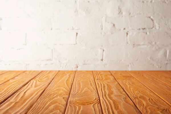 Orange wooden tabletop and white wall with bricks — Stock Photo