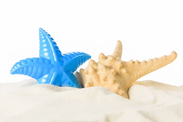 Spielzeug und echte Seesterne im Sand isoliert auf weiß — Stockfoto