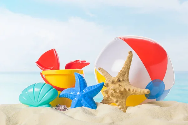 Palla da spiaggia e giocattoli in sabbia su sfondo cielo blu — Foto stock