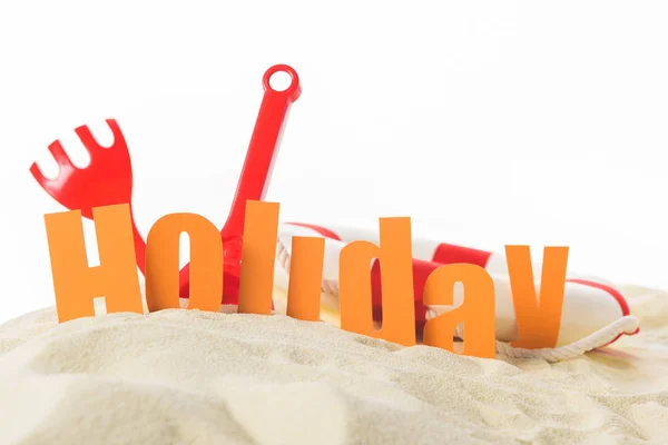 Beach toys and word Holiday in sand isolated on white — Stock Photo