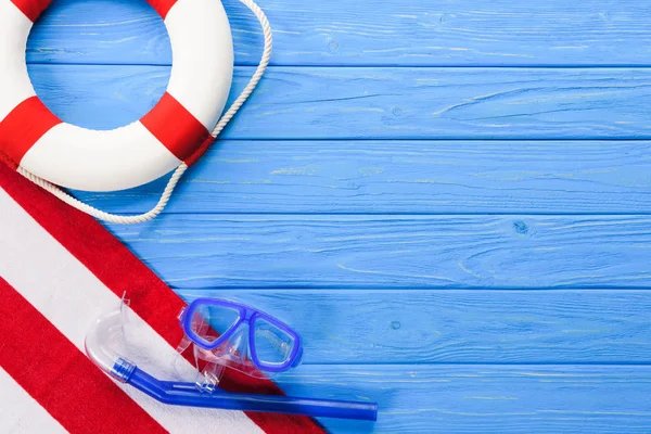 Rettungsring mit Maske und Handtuch auf blauem Holzhintergrund — Stockfoto