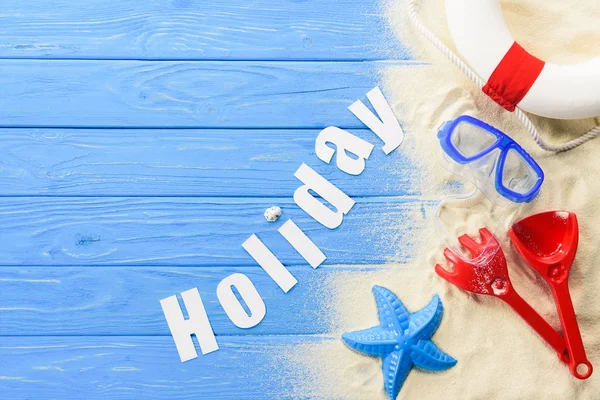 Пляжні іграшки та святковий напис на синьому дерев'яному фоні — стокове фото
