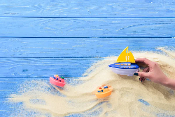 Mulher brincando com barco de brinquedo no fundo de madeira azul — Fotografia de Stock