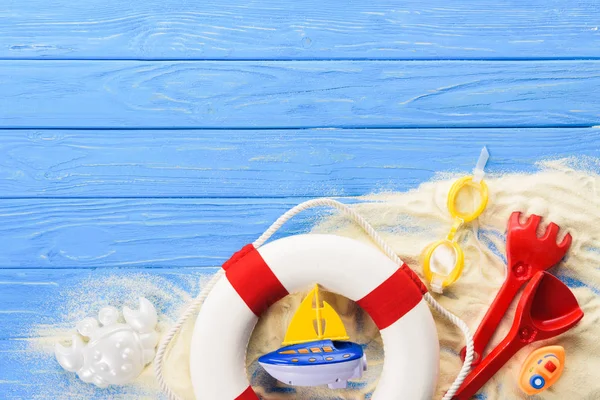 Anillo salvavidas y barcos de juguete sobre fondo de madera azul - foto de stock