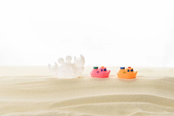 Іграшкові човни та краби в піску ізольовані на білому — стокове фото