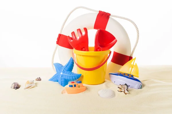 Anillo de vida y juguetes de playa en arena aislada en blanco - foto de stock