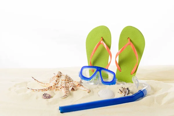 Tongs et masque de plongée avec coquillages dans le sable isolé sur blanc — Photo de stock