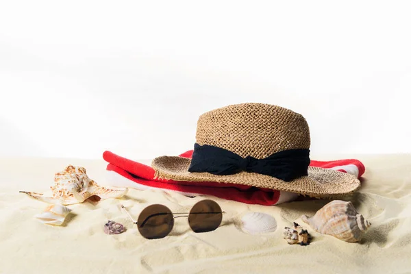 Sombrero de paja y gafas de sol con conchas marinas en arena aislada sobre blanco - foto de stock