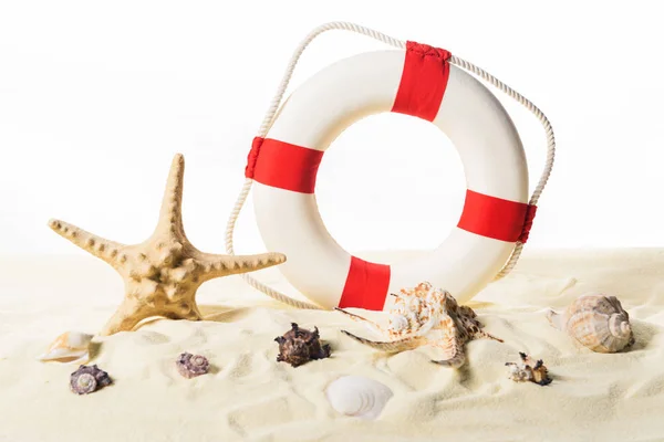 Life ring and seashells in sand isolated on white — Stock Photo