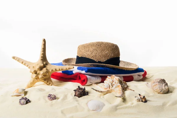 Coquilles et chapeau de paille dans le sable isolé sur blanc — Photo de stock