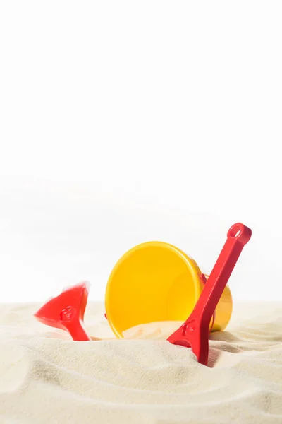 Cubo y juguetes de playa en arena aislada en blanco - foto de stock