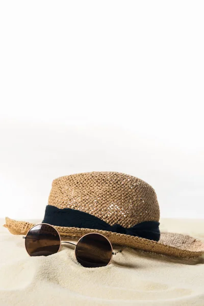 Солом'яний капелюх і сонцезахисні окуляри в піску ізольовані на білому — стокове фото