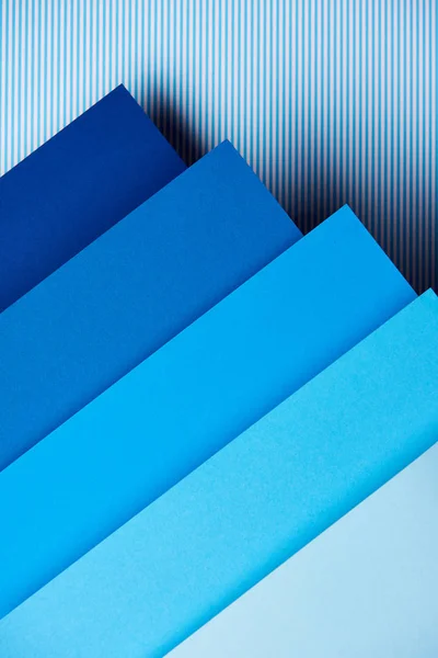 Paper sheets in blue tones on striped background — Stock Photo