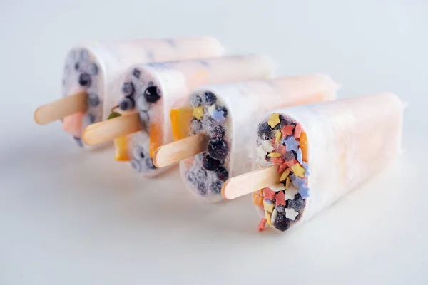 Close-up view of fresh frozen homemade popsicles with fruits and berries on grey — Stock Photo