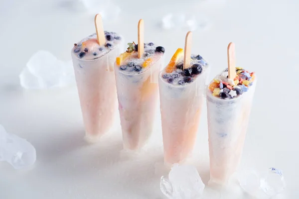 High angle view of sweet homemade ice cream with fruits and ice cubes on grey — Stock Photo