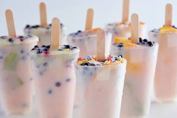 Крупный план сладкого домашнего фруктового мороженого с фруктами и ягодами в контейнерах на сером — стоковое фото
