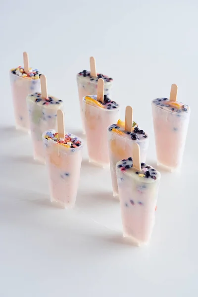 Tasty homemade popsicles with sticks in containers on grey — Stock Photo