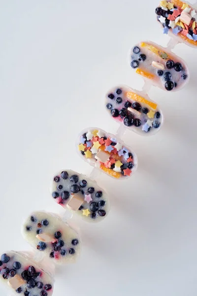 Вид зверху свіжих заморожених домашніх папуг з органічними фруктами та ягодами на сірому — стокове фото