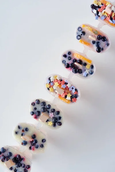 Vista dall'alto di ghiaccioli freschi surgelati fatti in casa con frutta biologica e bacche su grigio — Foto stock