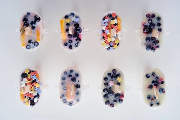 Blick von oben auf leckere hausgemachte Eis am Stiel mit Bio-Früchten und Beeren auf grau — Stockfoto
