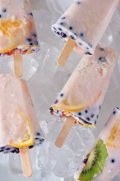 Vista ravvicinata di ghiaccioli fatti in casa gourmet con frutta e bacche su cubetti di ghiaccio — Foto stock