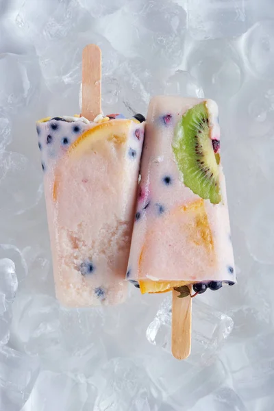 Top view of delicious homemade popsicles with fruits and berries on ice cubes — Stock Photo
