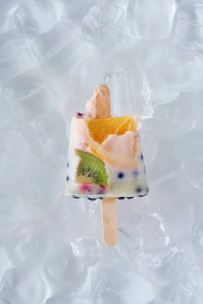 Vista close-up de metade no picolé caseiro com frutas e bagas em cubos de gelo — Fotografia de Stock