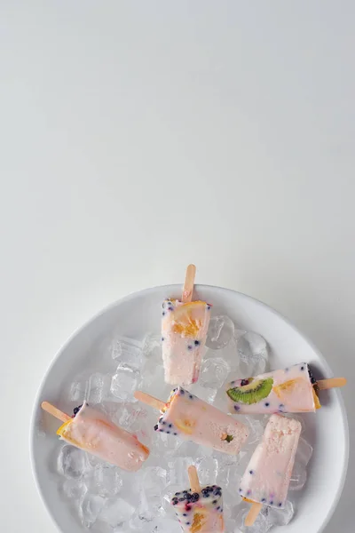 Top view of delicious homemade fruity popsicles with ice cubes on grey — Stock Photo
