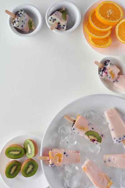 Top view of delicious homemade popsicles with ice cubes and sliced fruits on grey background — Stock Photo