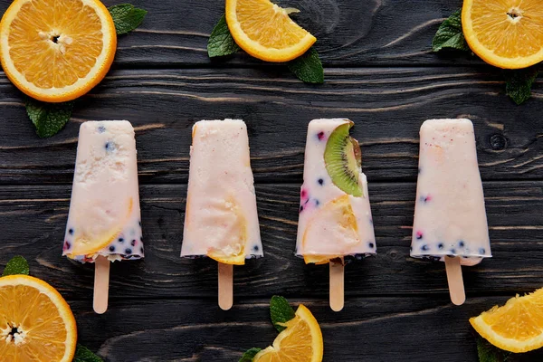 Blick von oben auf hausgemachtes Gourmet-Eis mit Orangenscheiben und Minze auf Holzoberfläche — Stockfoto