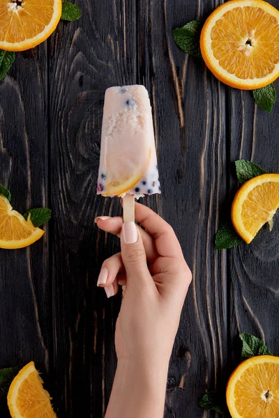 Foto recortada de la persona sosteniendo delicioso helado casero por encima de la mesa de madera - foto de stock