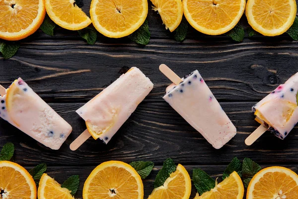 Top view of gourmet homemade popsicles with orange slices and mint on wooden surface — Stock Photo